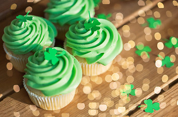 Image showing green cupcakes and shamrock on wooden table