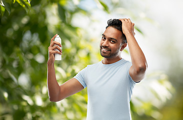 Image showing smiling indian man applying hair spray over gray