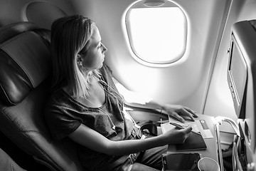 Image showing Casual woman flying on commercial passengers airplane, filling in immigration form.