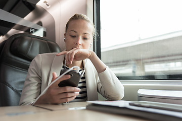 Image showing Businesswoman communicating on mobile phone while traveling by train.