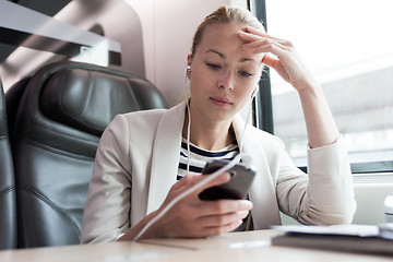 Image showing Businesswoman communicating on mobile phone while traveling by train.