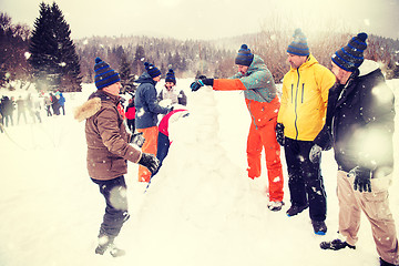 Image showing group of young people making a snowman