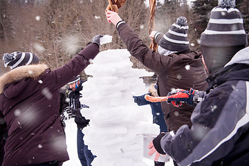 Image showing group of young people making a snowman