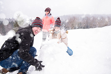 Image showing group of young people making a snowman