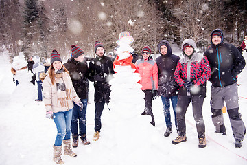 Image showing group portait of young people posing with snowman