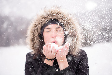 Image showing young woman blowing snow on snowy day