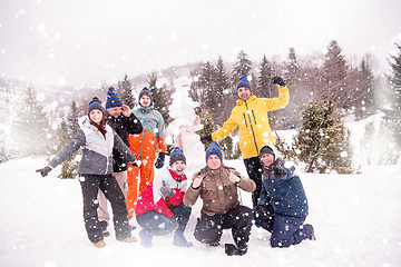 Image showing group portait of young people posing with snowman