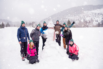 Image showing group portait of young people posing with snowman