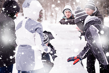 Image showing group of young people making a snowman