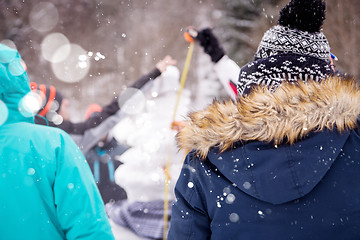 Image showing young people measuring the height of finished snowman