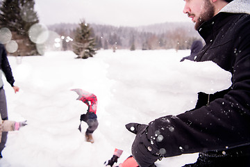 Image showing group of young people making a snowman