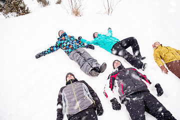 Image showing group of young people laying on snow and making snow angel