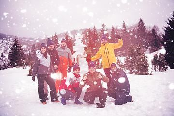 Image showing group portait of young people posing with snowman