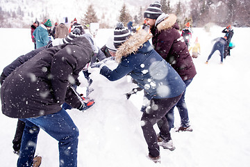 Image showing group of young people making a snowman