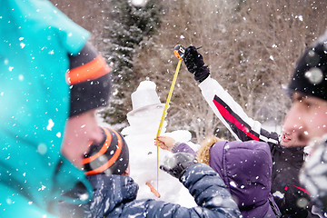 Image showing young people measuring the height of finished snowman