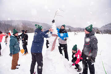 Image showing group of young people making a snowman