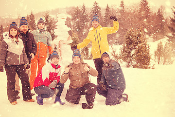 Image showing group portait of young people posing with snowman