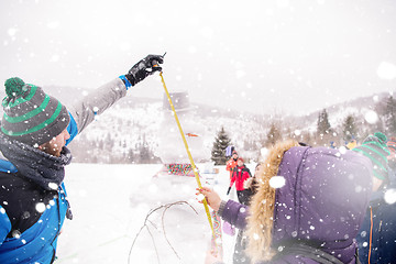 Image showing young people measuring the height of finished snowman