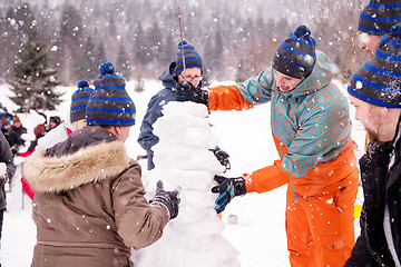 Image showing group of young people making a snowman