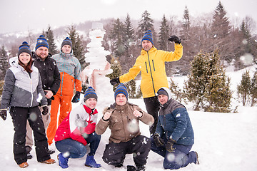 Image showing group portait of young people posing with snowman