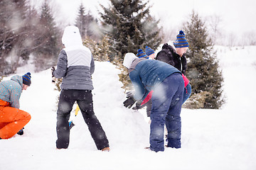 Image showing group of young people making a snowman