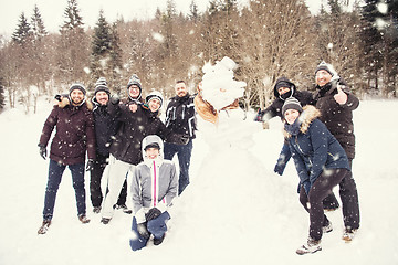 Image showing group portait of young people posing with snowman