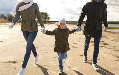 Image showing happy family running along autumn beach