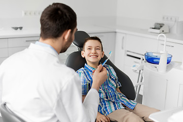 Image showing dentist giving toothbrush to kid patient at clinic