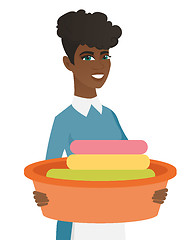 Image showing African housewife holding basin with dirty linen.