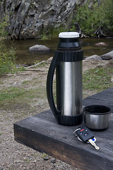 Image showing stop and rest when driving - car key, thermos bottle on picnic t