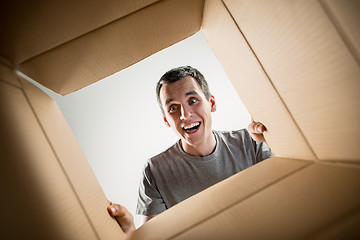 Image showing Man unpacking and opening carton box and looking inside