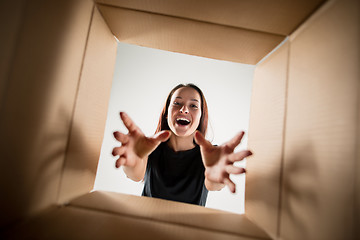 Image showing Woman unpacking and opening carton box and looking inside