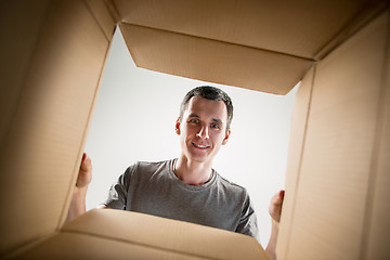 Image showing Man unpacking and opening carton box and looking inside