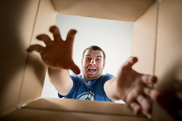 Image showing Man unpacking and opening carton box and looking inside