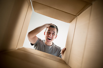 Image showing Man unpacking and opening carton box and looking inside