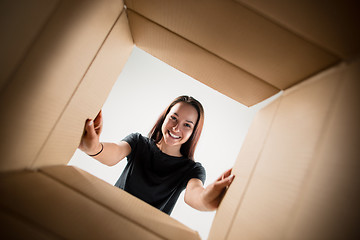 Image showing Woman unpacking and opening carton box and looking inside