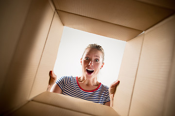 Image showing Woman unpacking and opening carton box and looking inside