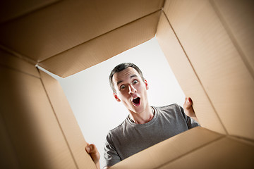 Image showing Man unpacking and opening carton box and looking inside