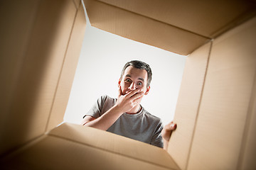 Image showing Man unpacking and opening carton box and looking inside