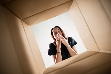 Image showing Woman unpacking and opening carton box and looking inside