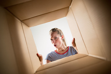 Image showing Woman unpacking and opening carton box and looking inside