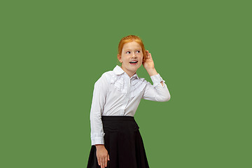 Image showing The young teen girl whispering a secret behind her hand over green background