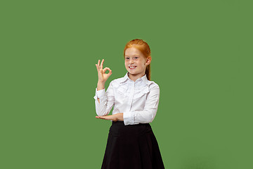 Image showing The happy teen girl standing and smiling against p green background.