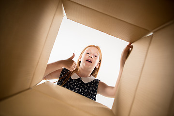 Image showing The girl unpacking and opening carton box and looking inside