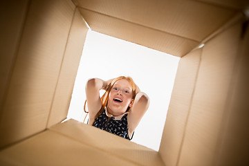 Image showing The girl unpacking and opening carton box and looking inside