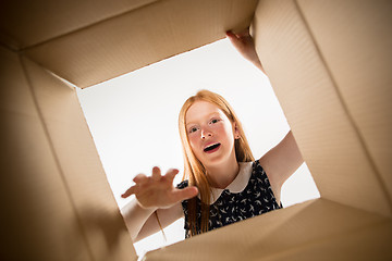 Image showing The girl unpacking and opening carton box and looking inside