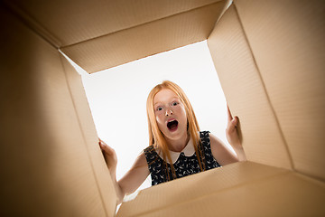 Image showing The girl unpacking and opening carton box and looking inside