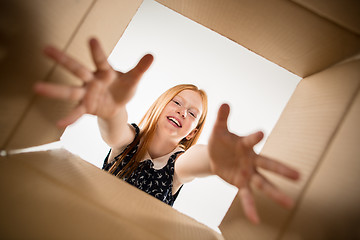 Image showing The girl unpacking and opening carton box and looking inside