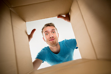 Image showing Man smiling, unpacking and opening carton box and looking inside