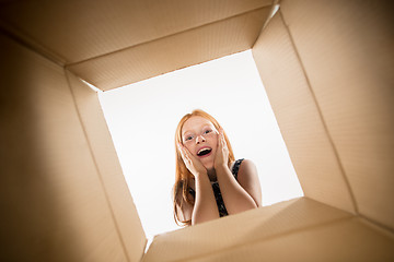 Image showing The girl unpacking and opening carton box and looking inside